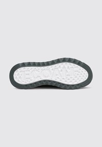 Suela de zapato con un borde de goma gris oscuro y una parte inferior blanca texturizada. Presenta un diseño de banda de rodadura con patrones triangulares y una marca en el centro.