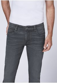 Gray denim jeans featuring a slim fit, five-pocket design, and a button closure. The fabric has a subtle texture and slight fading.