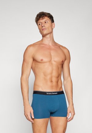 Boxers en coton bleu avec une ceinture élastique noire, arborant le nom de la marque "bruno banani" et un ajustement serré. Texture lisse et longueur courte.