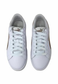 Białe sneakersy z gładką skórzaną cholewką, płaskimi sznurowadłami i teksturowanym noskiem. Brązowe akcenty po bokach. Wyściełane szare wnętrze.