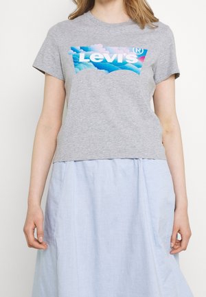 Graues kurzärmeliges T-Shirt mit einem blauen und pinken Levi's Logo-Grafik auf der Vorderseite, getragen über einem hellblauen, fließenden Rock.