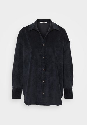 Black velvet button-up shirt with a collar, featuring a soft texture, long sleeves, and cream-colored buttons along the front placket.