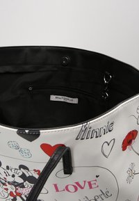 Sac à main blanc avec des accents noirs, présentant des graphismes Disney imprimés, incluant Minnie Mouse, des cœurs et des fleurs. L'intérieur est doublé de noir.