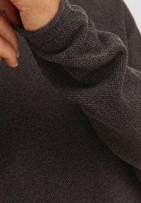 Gebreide trui in donkerbruin met een gestructureerd oppervlak. Heeft strakke manchetten en een zachte, flexibele stof voor comfort.