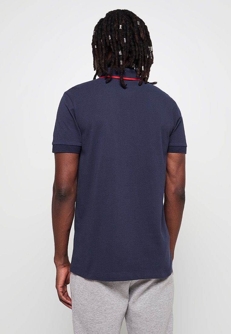 Polo bleu marine en coton doux avec des manches courtes et un col côtelé, présentant une subtile touche de rouge sur le col.