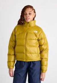 Rumena napihnjena jakna z visokim ovratnikom, vodoravnim kvadratnim vzorcem in sprednjim zadrgo. Okrašena z belim logotipom na levem prsnem delu.