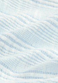 Tessuto azzurro chiaro con un aspetto texturizzato e lavorato a maglia, caratterizzato da strisce alternate di diversa larghezza. Il materiale appare morbido e leggero.