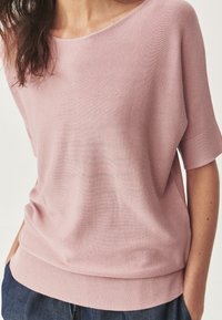 Roze gebreide top met een relaxte pasvorm, brede halslijn, korte mouwen en geribde zoom. Gladde textuur en subtiele horizontale strepen.