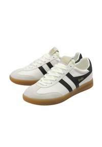 Witte en beige sneakers met zwarte strepen, rubberen zolen en "Gola" merknaam aan de zijkanten en tong, weergegeven als een paar vanuit een lichte hoek.