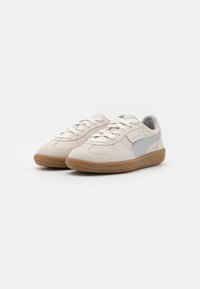 Bezsűrű nubuk sneakers szürke emblémával, fűzős kivitelben, textúrált gumi talppal és varrott részletekkel a felső részen.