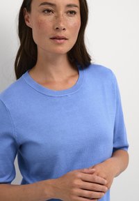 Lichtblauwe gebreide trui met een ronde hals en korte mouwen, met een gladde textuur en een eenvoudig, klassiek ontwerp.