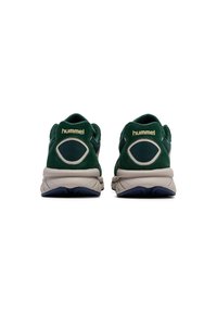 Gröna träningsskor i mocka och mesh-material, med en dämpad sula, framträdande hälstöd och en guld- eller märkeslogotyp bak på skon.