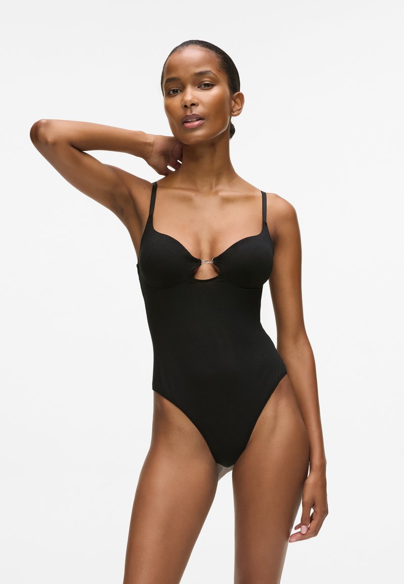 Juodas vientisas maudymosi kostiumėlis su reguliuojamomis petnešėlėmis, formuotais puodeliais ir iškirpimu krūtinės srityje. Lygus audinys, aukštos iškirpimo kojos dizainas.