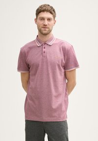 Kortærmet polo shirt i et meleret pink stof, med en krave med hvide og orange striber, tre-knaps placket og logo-detalje.