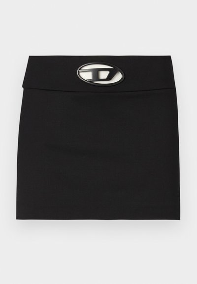 Mini-jupe noire avec une taille plate. Dotée d'une boucle logo métallique proéminente à l'avant. Fabriquée en tissu lisse sans motifs visibles.