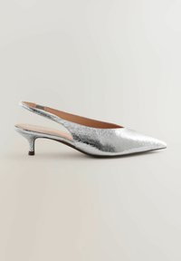 Zapato de tacón slingback plateado con punta afilada, parte superior metálica texturizada, tacón delgado y plantilla acolchada. Forro interior suave en beige.