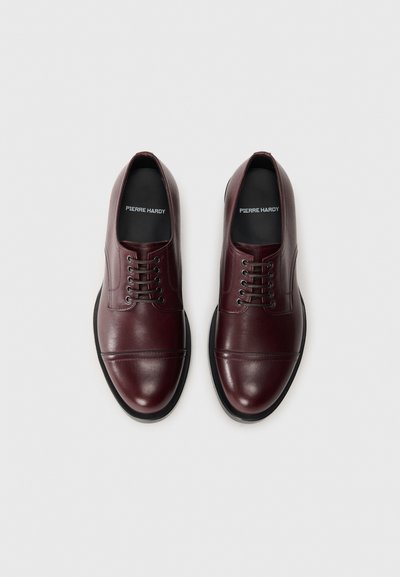Scarpe da uomo in pelle bordeaux con finitura liscia, punta rotonda e allacciatura a sei fori. Suola in gomma nera con dettagli di cucitura discreti.