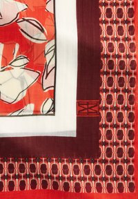 Kleurrijke sjaal met een bloemontwerp in rood en wit, omzoomd met een effen kastanjebruine rand en een geometrisch patroon in rood en wit.