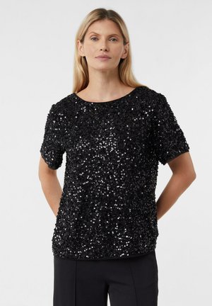 Black sequined short-sleeve top with a round neckline, textured surface, and relaxed fit. Worn with black tailored pants.