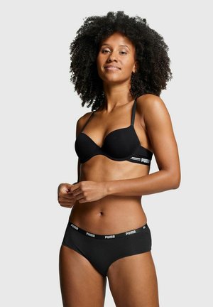 Schwarzer BH mit dünnen Trägern und geformten Cups, kombiniert mit passenden schwarzen Panties, die ein weißes Markenlogo am Bund tragen. Glatte Textur.