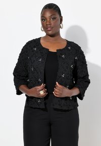 Schwarze dekorative Jacke aus strukturiertem Stoff, mit floralen Motiven und Pailletten. Verfügt über einen runden Halsausschnitt und drei Viertelärmel.