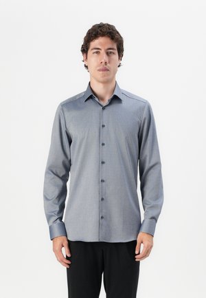 Long-sleeve blue patterned shirt with a collared neckline, front buttons, and a smooth texture. Worn with black pants.