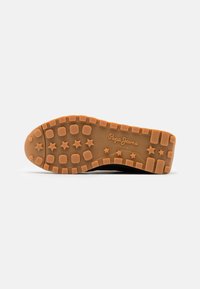 Semelle de chaussure avec une bande de roulement en caoutchouc marron présentant des motifs d'étoiles et de carrés et le logo "Pepe Jeans London" au centre.