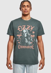 Mørkegrå bomulds t-shirt med et grafisk tryk af en musiker med solbriller, palmetræer og tekst i pink, der skaber en markant visuel kontrast.