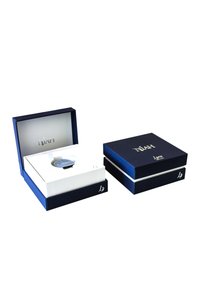 Boîte à montre bleu marine avec un insert blanc. Elle présente une finition brillante, une lettrage doré et un couvercle contrastant mettant en valeur la montre à l'intérieur.