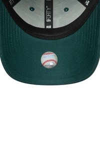 Grüne Baseballkappe mit schwarzem Schirm, auf dem Schirm befindet sich ein runder Aufkleber eines Baseballs mit roter Naht und Text.