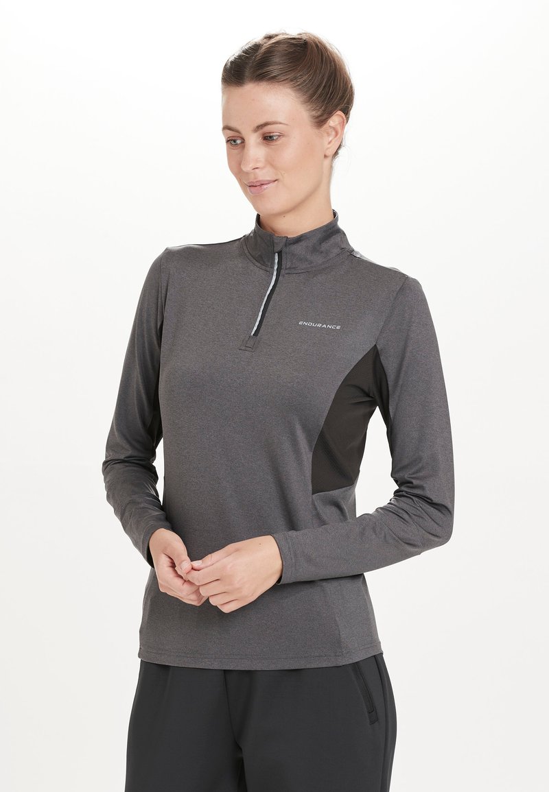 Grå langærmet atletisk top med halv-zip krave, sorte sidelapper og refleksdetaljer. Lavet af et glat, åndbart stof.