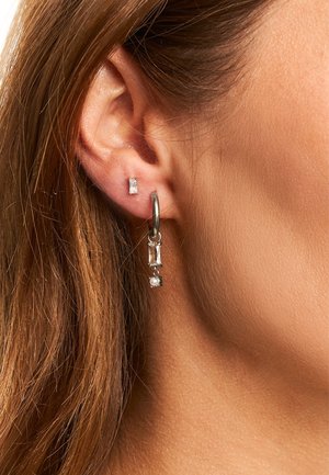 Boucles d'oreilles en argent avec des pierres précieuses claires rectangulaires et un petit détail en perle. Une puce d'oreille complète le design, mettant en valeur des pierres transparentes.