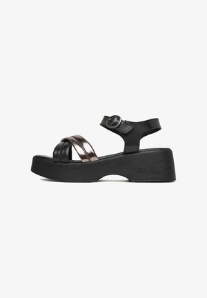 Sandalias de plataforma negras con upper de cuero, una correa metálica, hebilla ajustable en el tobillo y suela de goma texturizada.