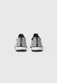 Sorte og hvide mønstrede sneakers med en tekstureret overflade, der har en trækflig og en sort accentstribe på hælen.