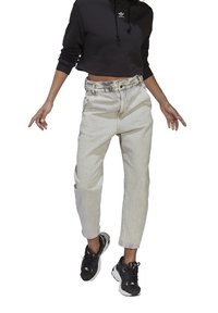 Ljusgråa denimjeans med hög midja och avslappnad passform, kombinerade med en svart kort hoodie med en liten vit logotyp.