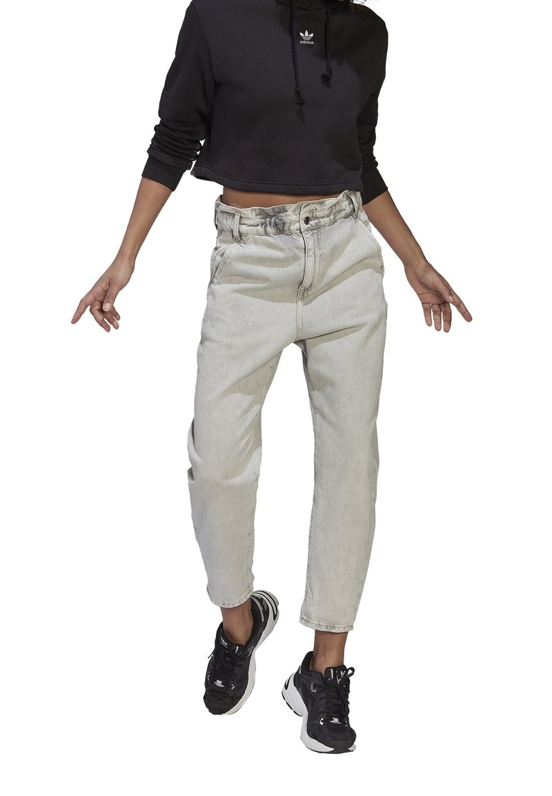 Ljusgråa denimjeans med hög midja och avslappnad passform, kombinerade med en svart kort hoodie med en liten vit logotyp.