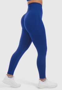 Leggings blu a vita alta realizzati in materiale elasticizzato, con una texture liscia e un design affusolato. Include un dettaglio con cucitura laterale.