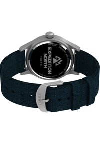 Reloj de acero inoxidable plateado con una esfera negra, correa de tela azul y hebilla de acero inoxidable. Presenta la marca "Expedition North".