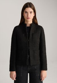 Zwarte textuur blazer met een licht gestructureerde pasvorm, voorzien van een ronde halslijn, zonder knopen en twee voorzakken.