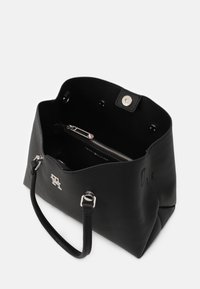 Črna usnjena torba z teksturo, z zgornjim odprtjem, srebrno kovino, notranjim žepom na zadrgo in logotipom na sprednji strani.