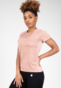 Korte mouwen sportshirt in een gemêleerd lichtoranje met textuurstof en zijpanelen van mesh. Gecombineerd met zwarte leggings met accenten.