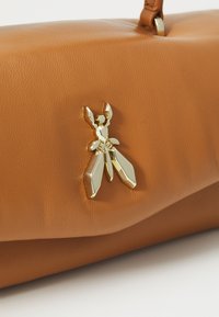 Sac à main en cuir marron au design élégant, avec un accent en forme d'insecte doré sur le devant pour une touche distinctive.
