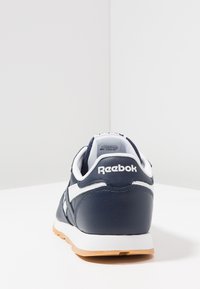 Sneaker in pelle blu con dettagli bianchi e suola in gomma. Presenta una linguetta e un tallone imbottiti, con il logo Reebok sul retro. Design classico.