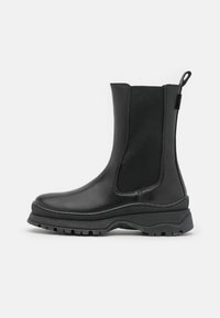 Černé kožené kotníkové boty s elastickými bočními panely, silnou texturovanou podrážkou a poutkem pro snadné nazouvání. Disponují hladkým povrchem a odolnou konstrukcí.