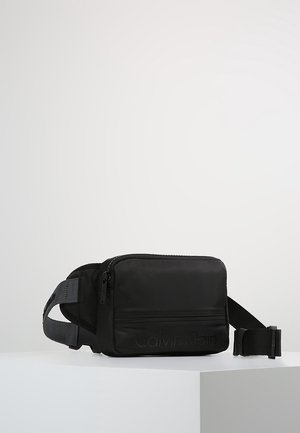 Svart nylon crossbody-väska med dragkedjestängning, justerbar rem och präglat logo på framsidan. Rektangulär form med slät yta.