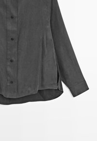 Dark gray long-sleeve shirt in lightweight fabric, featuring a button-up front, side slits, and a curved hem. Button accents are black.