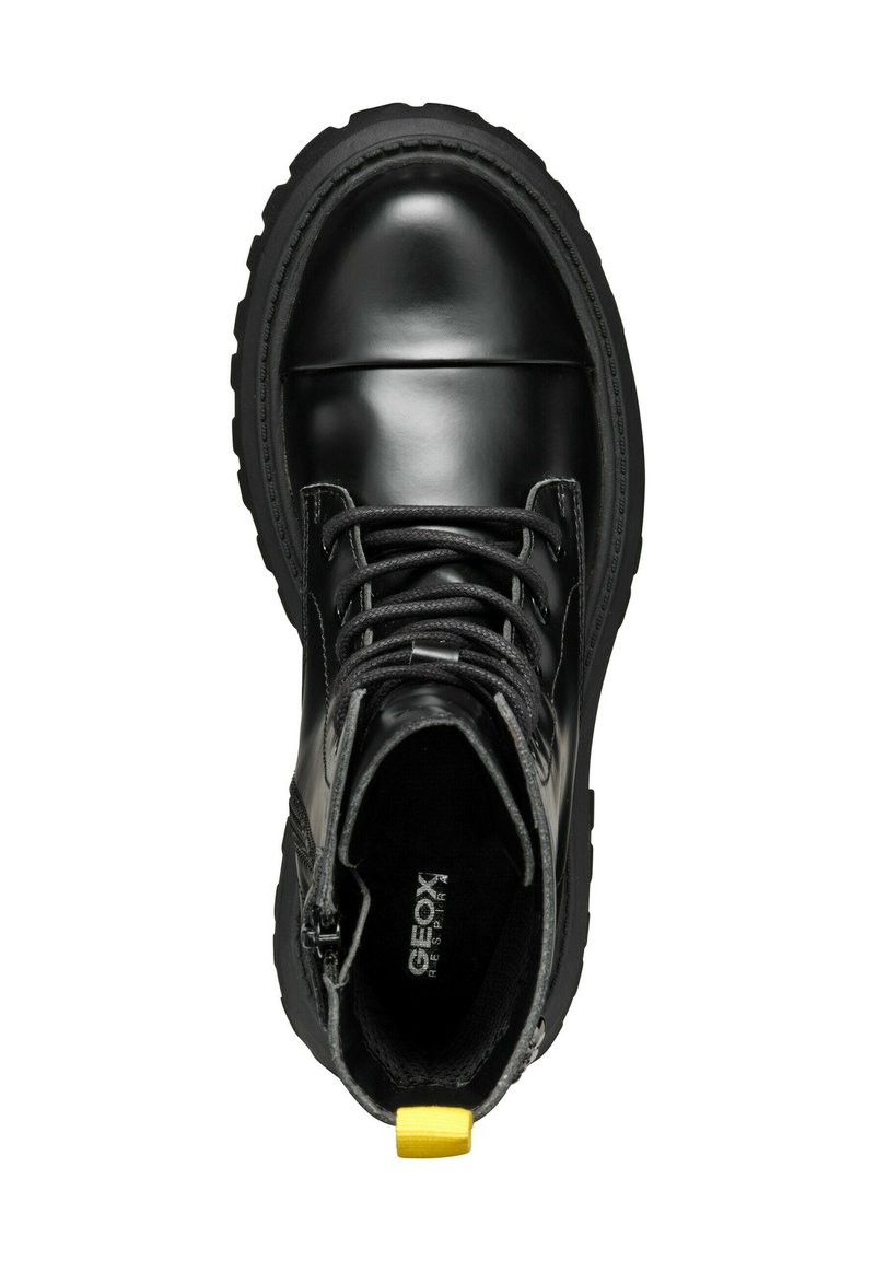 Stivale alla caviglia in pelle nera con linguetta testurizzata, punta rotonda, cuciture rinforzate e un'etichetta gialla sul tallone. Presenta lacci neri e suola in gomma.