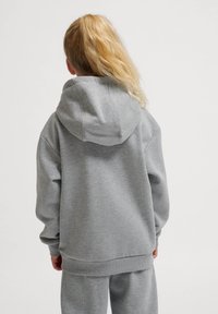 Szary hoodie z dużym, strukturalnym kapturem, ściągaczami przy mankietach i u dołu, luźny krój, wykonany z miękkiej tkaniny bawełnianej. Minimalistyczny design.
