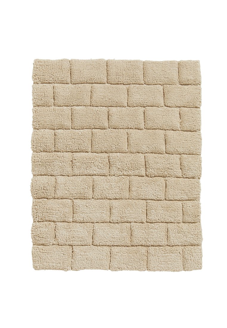 Beżowy prostokątny dywan z fakturowanym wzorem cegieł, wykonany z miękkiego, puszystego materiału o grubej, chłonnej powierzchni.