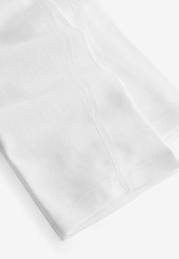 Weiße Baumwollleggings mit glatter Textur. Verfügt über flache Nähte und ein körperbetontes Design, das einen minimalistischen Stil betont. Keine Muster oder Akzente.